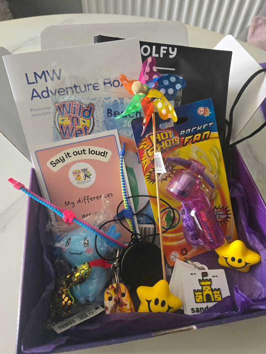 Beach Themed June Box with colorful toys, books, pinwheel, and star-shaped items in a purple gift box