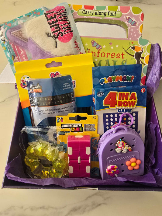 Travel themed box with sleep mask, activity book, fidget cube, coloring pencils, travel cushion, connect 4 game, mini charm bag, jelly bracelet, and autism wellbeing card